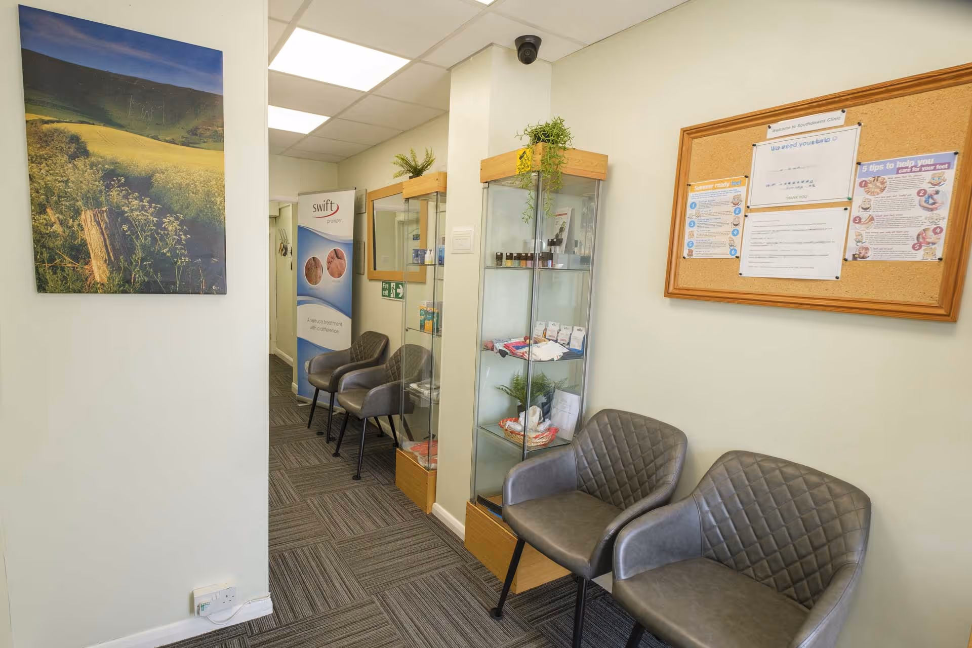 Two gray chairs in a waiting room with informational posters and a display cabinet.